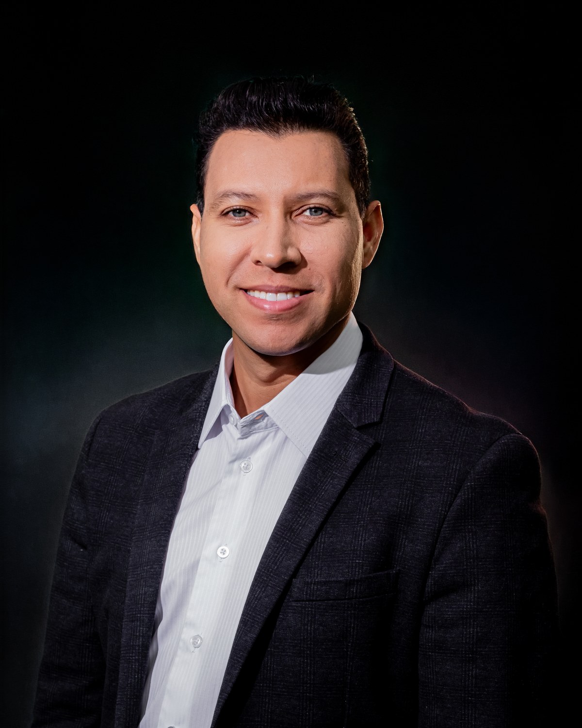 Retrato de estúdio de Alex Sandro, de terno escuro e camisa clara, sobre fundo escuro
